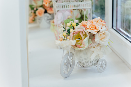 Lilacs and pink roses flowers in a decorative white wooden bicycle on a window .Floral gift for a wedding or birthday.の写真素材