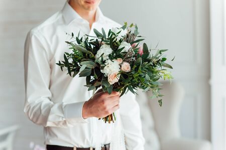 Beautiful wedding bouquet in hands of the groom.の写真素材