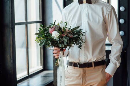 Beautiful wedding bouquet in hands of the groom.の写真素材