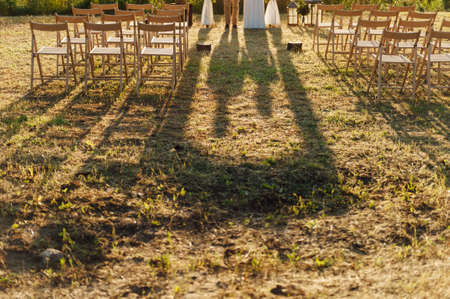 lovers hold hands and stand near the wedding arch. long shadows at sunsetの写真素材