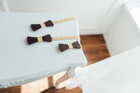 three Wooden bow ties on a wooden table.の写真素材