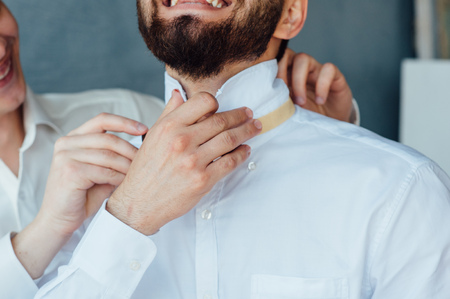 groom wears stylish bow tie using friend.