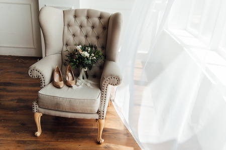 bridal bouquet of peones, wedding flowers for the ceremony on the chair in a hotel room with white shoes.の写真素材