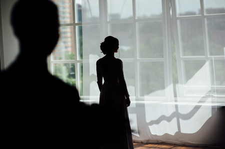 silhouette of a girl near the window , which is waiting for her boyfriendの写真素材