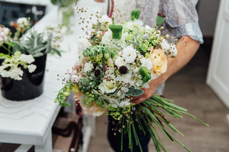 Florist finishing beautiful and rich spring flower arrangementの写真素材