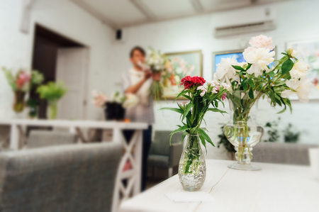 Beautiful spring flowers in glass vases on light white backgroundの写真素材
