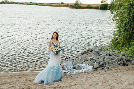 Beautiful young bride woman in luxury wedding dress with red lips makeup and long wavy hairstyle....