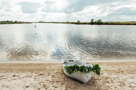 lonely white boat on the bank of the river , decorated with flowersの写真素材