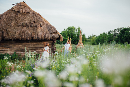 Happy Bride and groom walking on the green grass near the river, smiling and kissing. couple having fun near the wooden houseの写真素材