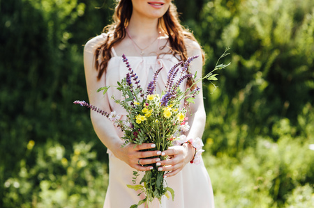 beautiful pregnant woman holding wildflowers at the parkの写真素材