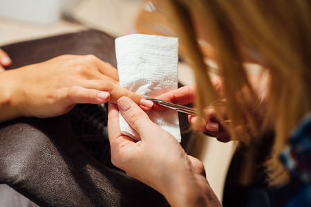 Woman in salon receiving manicure by nail beauticianの写真素材