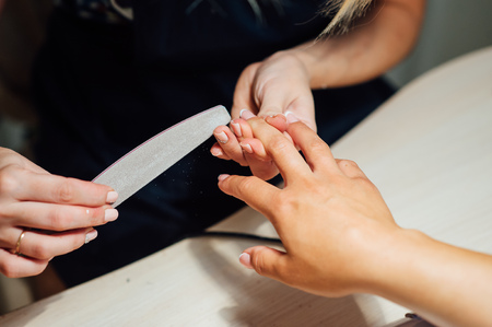 Woman in salon receiving manicure by nail beauticianの写真素材