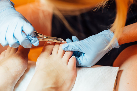 Master pedicure in sterile gloves shapes nails and cuticles closeup . Hardware manicure. Concept body care.の写真素材