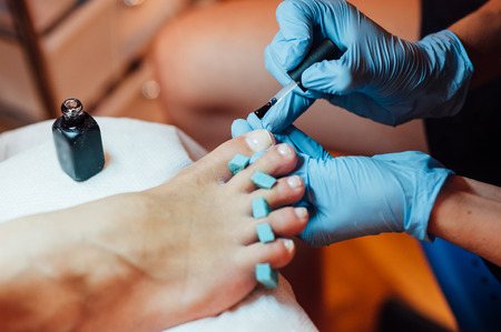 Master pedicure in sterile gloves shapes nails and cuticles closeup . Hardware manicure. Concept body care.