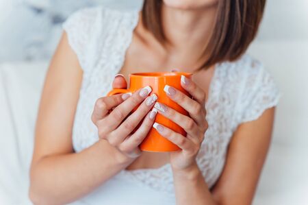 Beauty bride in night gown is drinking coffee indoors. Beautiful model girl in a white wedding dress. Female portrait of cute lady. Woman with hairstyleの写真素材
