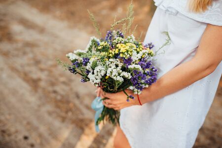 Beautiful bouquet of wild flowers in the hands of a girlの写真素材