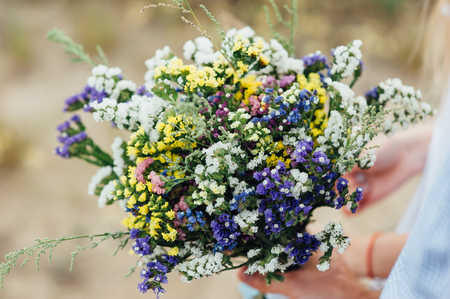 Beautiful bouquet of wild flowers in the hands of manの写真素材
