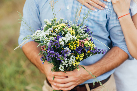 Beautiful bouquet of wild flowers in the hands of manの写真素材