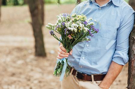 Beautiful bouquet of wild flowers in the hands of manの写真素材