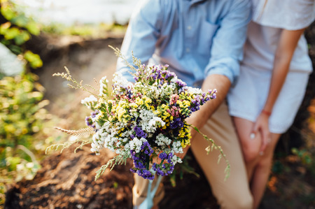 Beautiful bouquet of wild flowers in the hands of manの写真素材