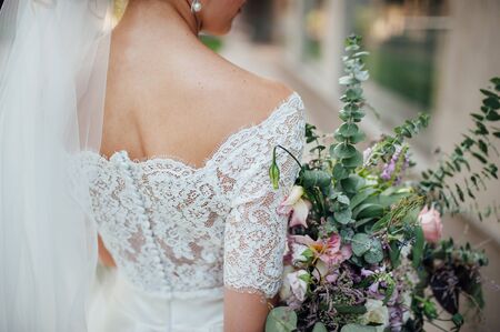 beautiful bouquet in hands of the bride is very stylish with light hair and lace dress