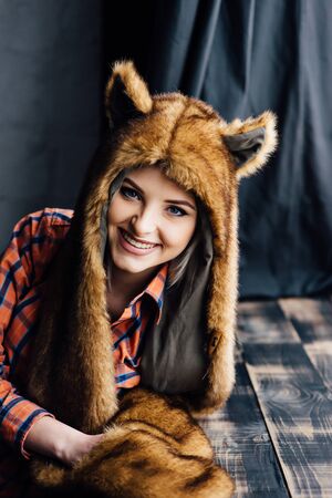 beautiful sexy girl wearing plaid shirt and brown fur hat with funny ears. Close portrait at the windowの写真素材