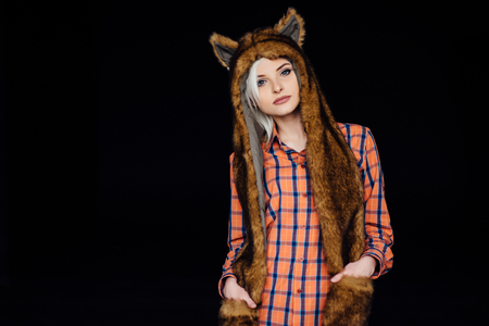 beautiful sexy girl wearing plaid shirt and brown fur hat with funny ears. Close portrait on dark backgroundの写真素材