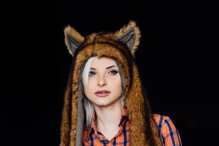 beautiful sexy girl wearing plaid shirt and brown fur hat with funny ears. Close portrait on dark backgroundの写真素材