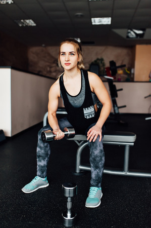 Sporty girl doing exercise with dumbbells in the gymの写真素材