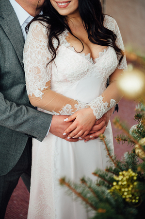 Winter Wedding .Lovers bride and groom in christmas decoration . Groom and bride together. Bride with a large and beautiful breasts. Couple hugging. Wedding day. Beautiful bride and elegant groom walking after wedding ceremony.の写真素材