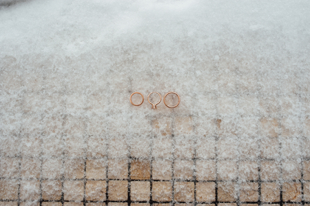 Wedding and engagement rings in gold on the snowの写真素材
