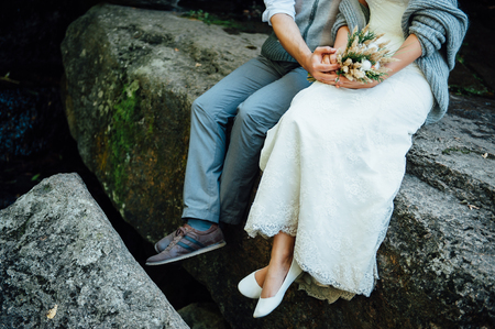 Close up portrait of a hugging couple sitting on a rock. A man gently hugs his girlfriendの写真素材
