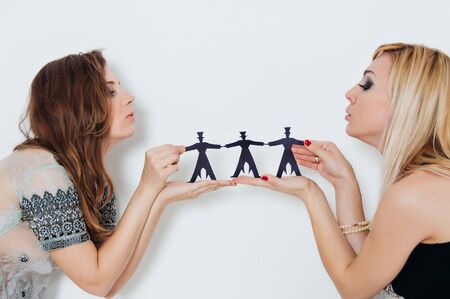 Close-up of women hands holding paper people over body background isolated on white background. People, population, friendship concept.の写真素材