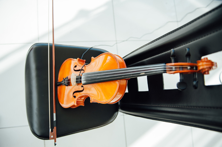 The classic violin was put on black chair.in blurry background .focus at violin .at studio's room prepare for practice.の写真素材