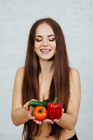 Beautiful girl with braces holding vegetablesの写真素材