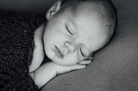 beautiful newborn sleeping baby boy with knitted hat on a wooden backgroundの写真素材