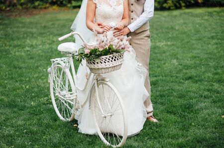Pretty young bride and groom with bicycle in parkの写真素材
