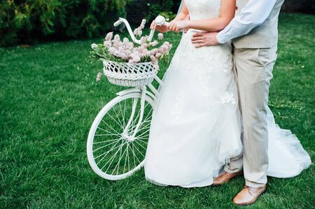 Pretty young bride and groom with bicycle in parkの写真素材
