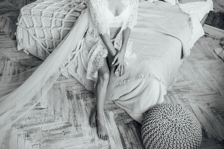 Beautiful bride in lingerie and white dress. charming girl shows her sexy legsの写真素材