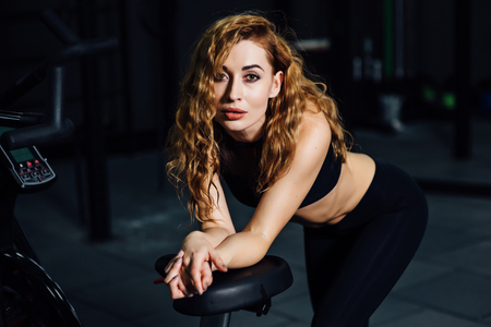 athletic girl stand near a bicycle simulatorの写真素材