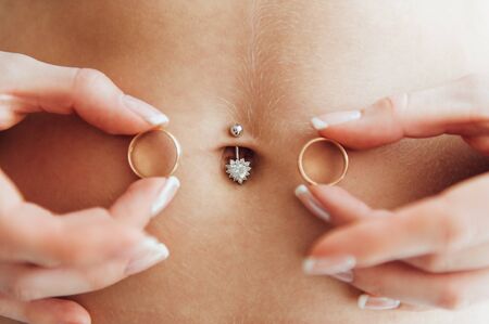 sexy bride in lingerie holds rings near her bellyの写真素材