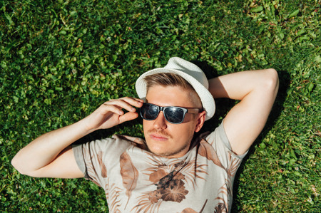 stylish hipster guy lying on the grass