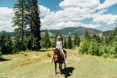 Lovely girl riding a horse in the mountainsの写真素材