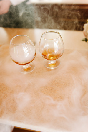Glasses of whiskey with smoke on wooden tableの写真素材