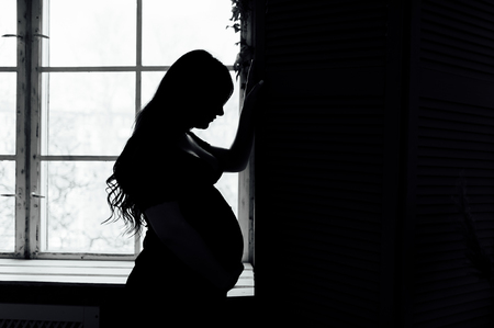 Silhouette of pregnant woman at her homeの写真素材