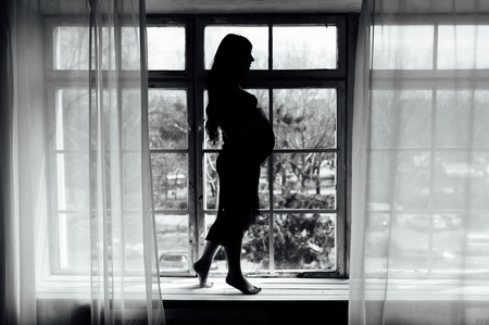 Silhouette of pregnant woman at her homeの写真素材