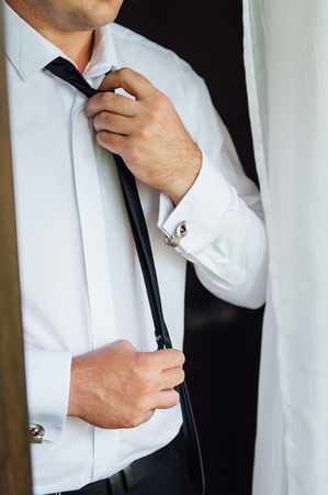 Close-up of a man in a tux fixing his vintage cufflink. groom bow tie cufflinksの写真素材