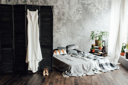 amazing wedding dress hanging on the screen near the gray bed in the loft room.の写真素材