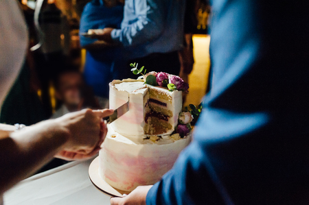 Wedding ceremony. Bride and groom cutting cake.の写真素材