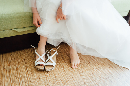 the bride puts on white shoes on feetの写真素材